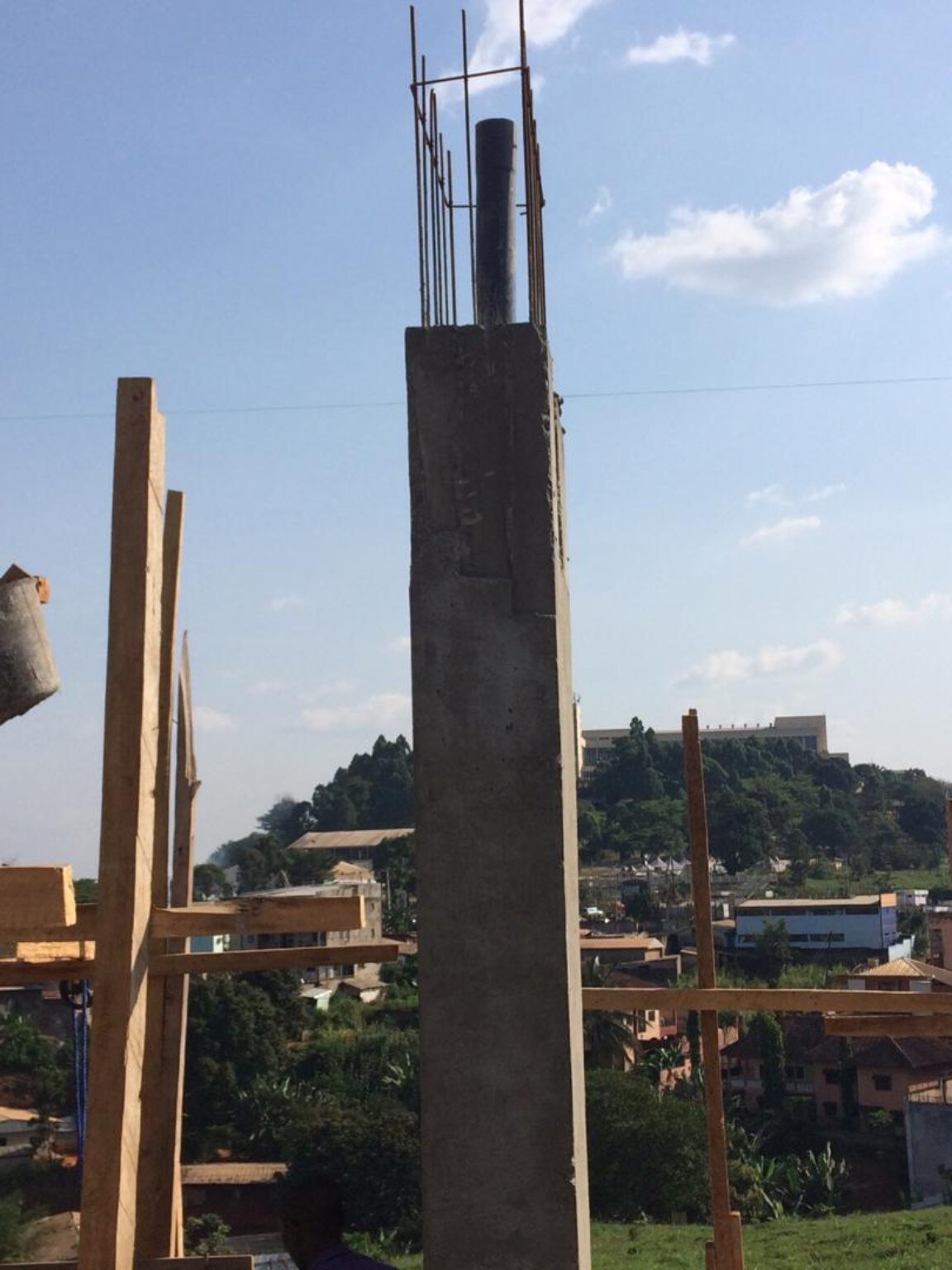 Close construction view of a roof-water downpipe positioned within the reinforcement of a vertical concrete façade fin at Golf Residences.