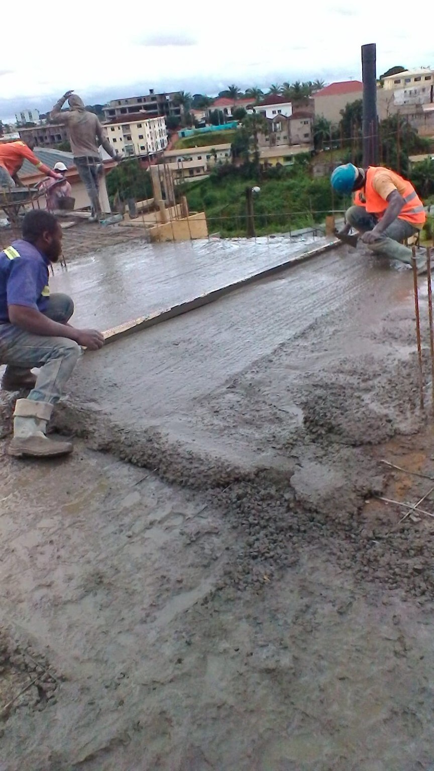 Construction team placing and leveling concrete during an upper-level slab pour at Golf Residences in Yaoundé.